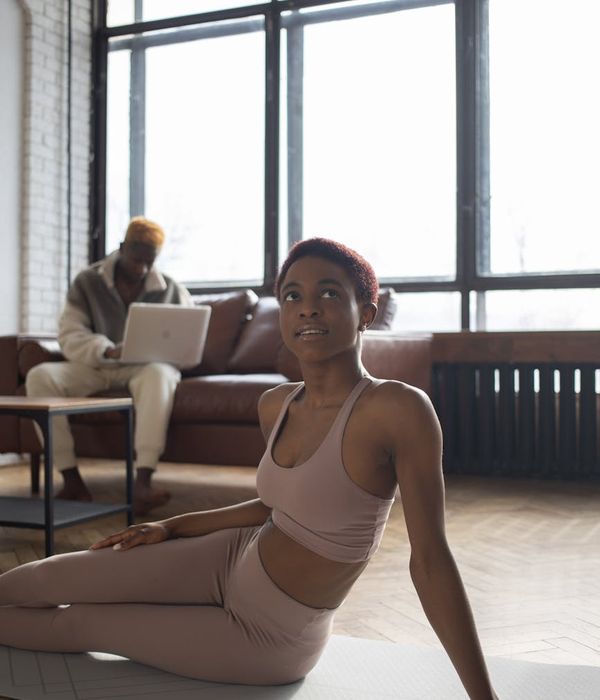 Person in comfortable sportswear stretching in a sunlit room.